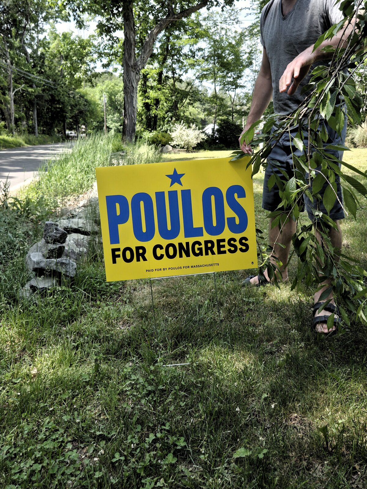 A supporter standing beside a Jason Poulos for Congress lawn sign