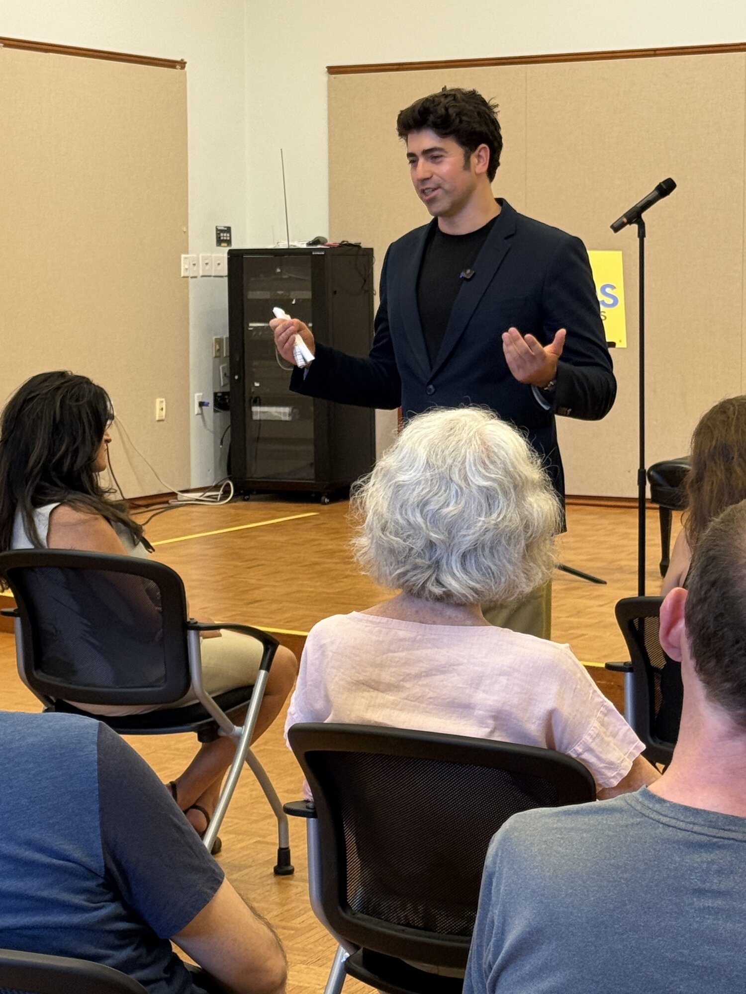 Jason Poulos speaking to a seated audience at a campaign town hall in MA-04, July 1, 2026